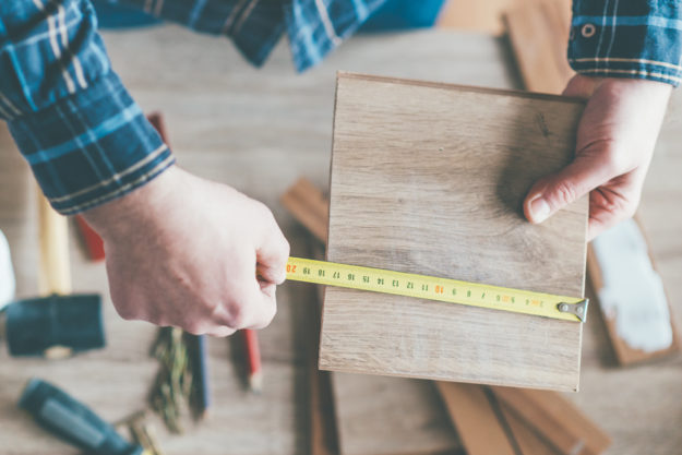 Carpenter measure wooden board in his workshop.