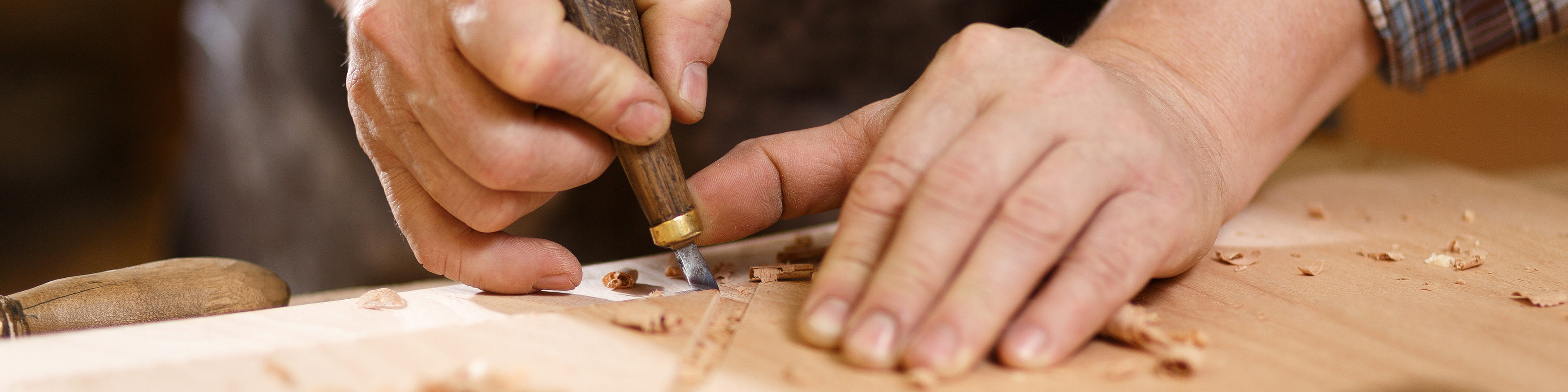 Carpenter with chisel in the hands on the workbench