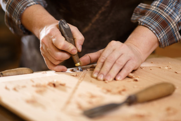 Carpenter with chisel in the hands on the workbench